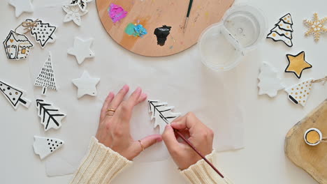 woman hand paints christmas ornaments with watercolor