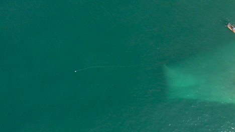 Aerial-top-down-view-of-fisherman-boats-with-the-fishnet-being-laid-over-the-surface-of-water-for-catching-fish