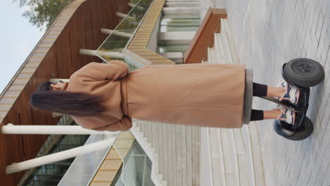 woman riding a self-balancing unicycle outside a modern building