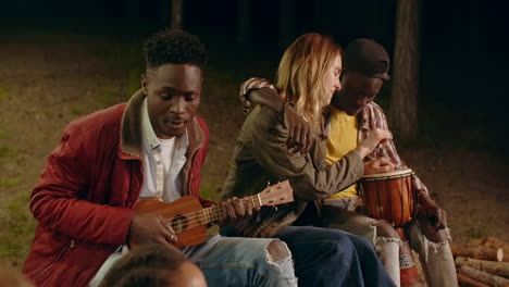 friends playing music around a campfire at night