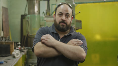 caucasian male factory worker at a factory standing with arms crossed looking to the camera