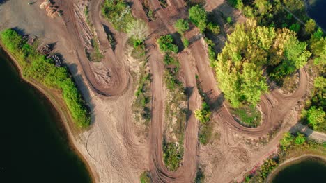 aerial drone top down view of a motocross track nestled within a scenic lake