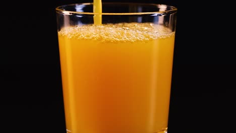 eine sequenz, in der orangensaft in ein glas gegossen wird, blasen erzeugt und sich reibungslos füllt.