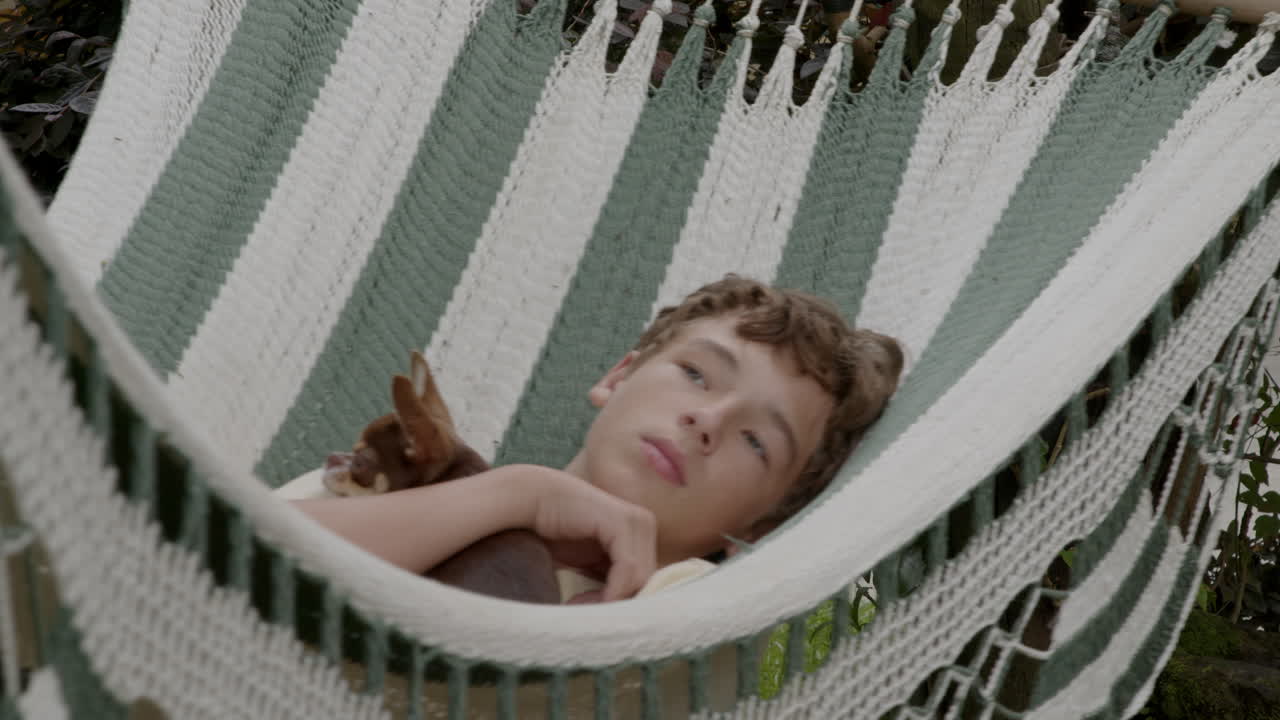 adolescente y perro relajándose en una hamaca