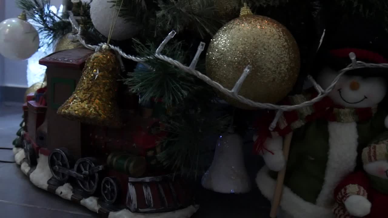 recorra los adornos navideños alrededor de la base de un árbol de navidad bellamente decorado