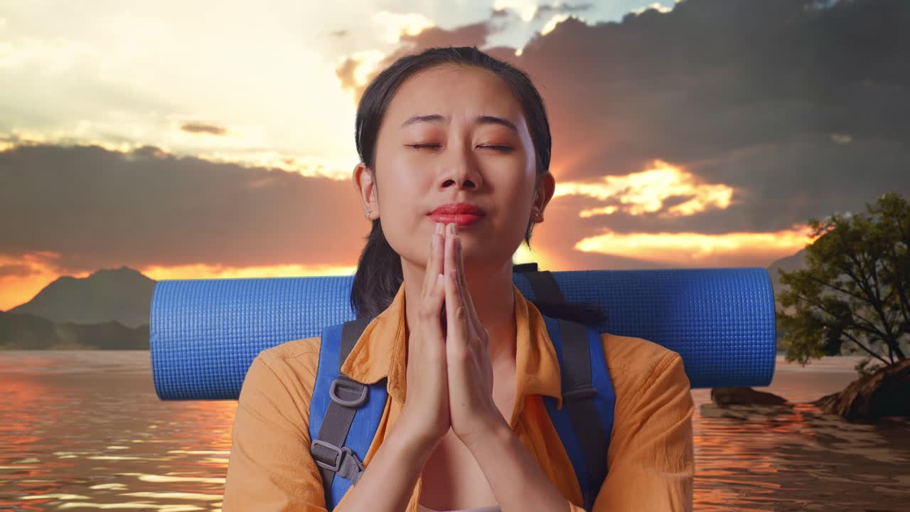 Close Up Of Asian Female Hiker With Mountaineering Backpack Pray For Something While Standing At A Lake During Sunset Time