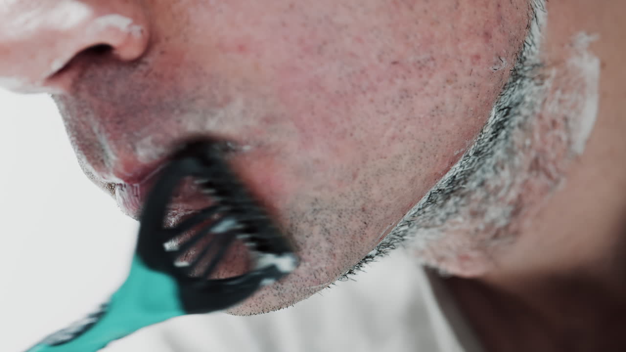 Close up of a man shaving his beard with a razor