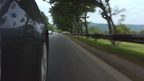 side of a moving vehicle showing both road and spinning wheels_1