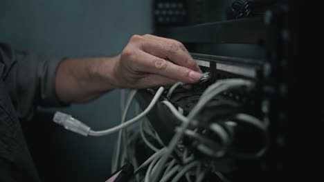 person connecting network cables in a server room