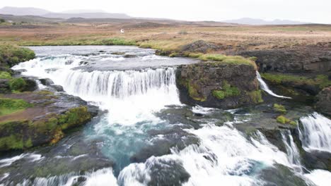 aerial: reveal reykjafoss waterfall presents itself as a powerful cascade of water