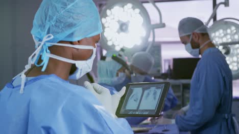 Nahaufnahme-Eines-Afroamerikanischen-Männlichen-Chirurgen,-Der-Im-Operationssaal-Des-Krankenhauses-Ein-Digitales-Tablet-Verwendet