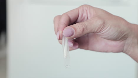 hand holding a medical transparent tube with swab sample - covid-19 swab test - closeup shot, slow motion