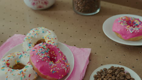 Person-picking-in-slow-mo-a-cup-of-coffee-in-a-table-with-various-glazed-doughnuts