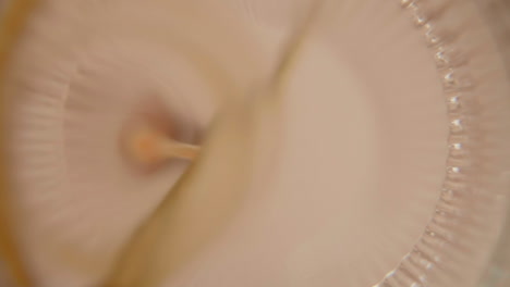a orange cold pressed juice getting poured into a drinking glass with a metal straw during detox cleanse slow motion looking up