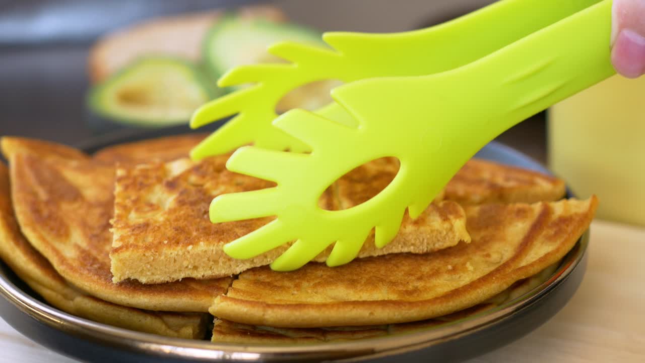 primer plano de pinzas apilando comida para los niños para el almuerzo en la escuela. los panqueques apetitosos preparados por la madre son disfrutados por niños y adultos