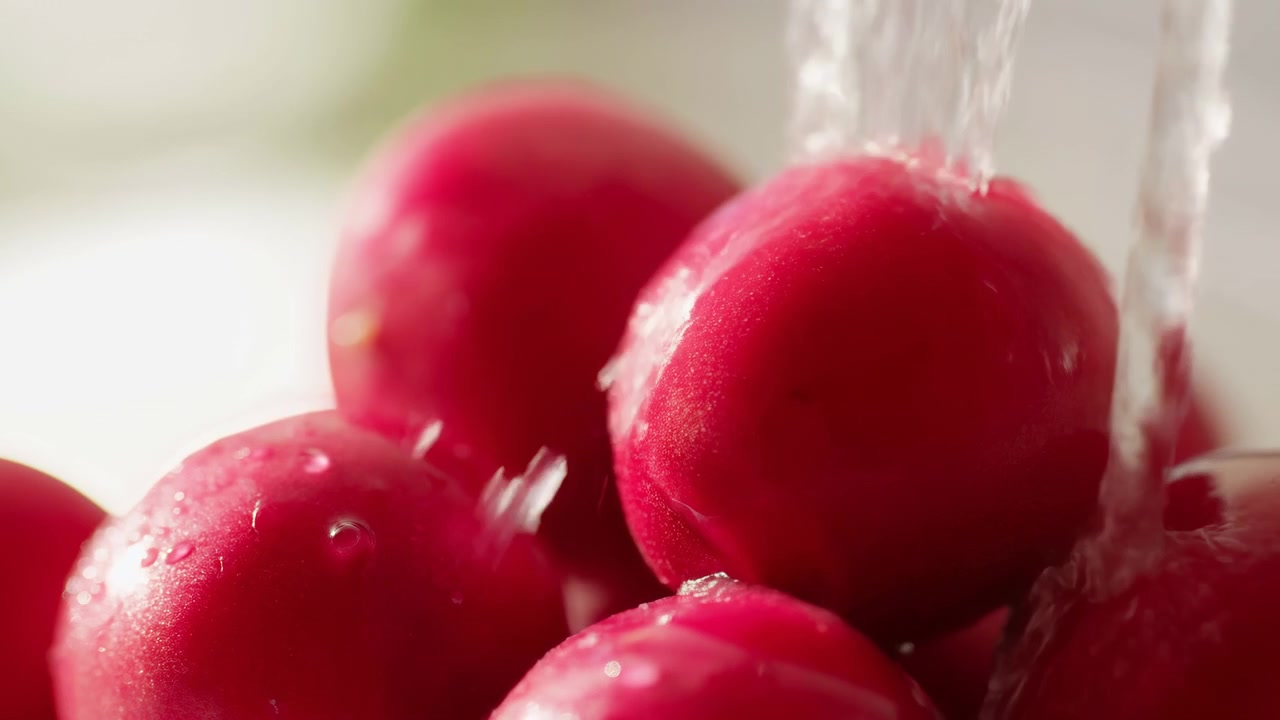 Prima sequenza di mele rosse raggruppate in un ambiente di cucina luminoso mentre acqua limpida si versa sui frutti, creando schizzi e goccioline.