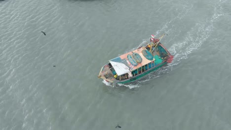 Aerial-Follow-shot-of-Fishing-boat-traveling-towards-the-harbor-from-the-sea-in-the-evening,-shot-with-a-drone-in-4k