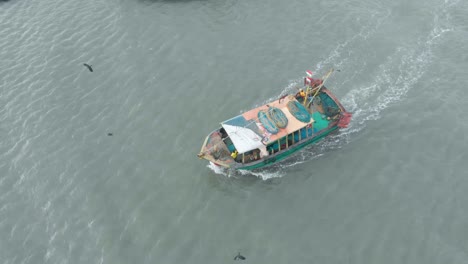 aerial follow shot of fishing boat traveling towards the harbor from the sea in the evening, shot with a drone in 4k