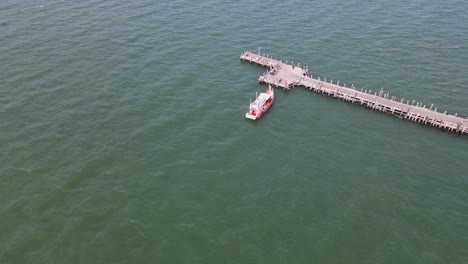 imágenes aéreas descendentes que revelan el muelle de pesca de pattaya con un barco y algunos vehículos en pattaya, tailandia