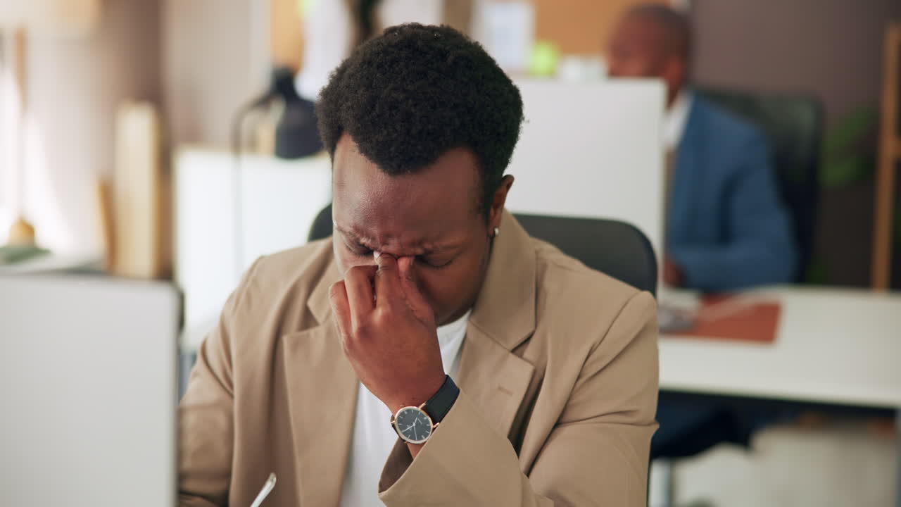 African American Man Experiencing Eye Strain and Fatigue While Working in Office