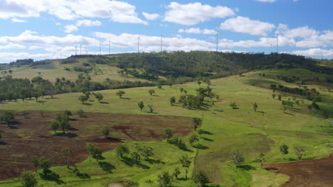 wind turbines create green energy on the hill top, wide, drone tilt up shot