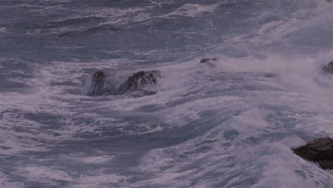 Close-up-of-waves-crashing-over-coastal-rocks