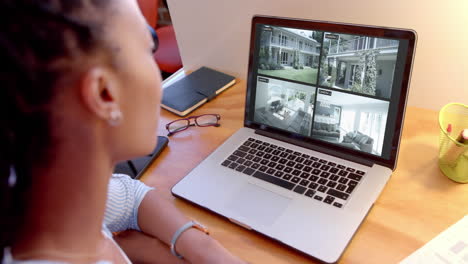 mujer afroamericana viendo cámaras de cctv en su computadora portátil, cámara lenta