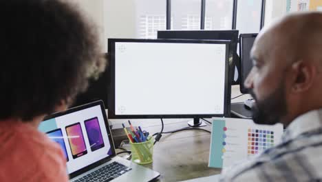 Two-happy-diverse-designers-in-discussion-at-computer-with-copy-space-in-casual-office,-slow-motion