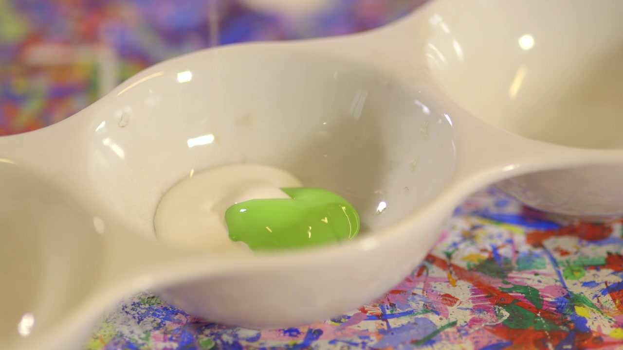 Tinta verde pinga em uma bandeja de tinta branca em um plano detalhe. Preparação artística com cores vivas, textura líquida e espaço de trabalho criativo