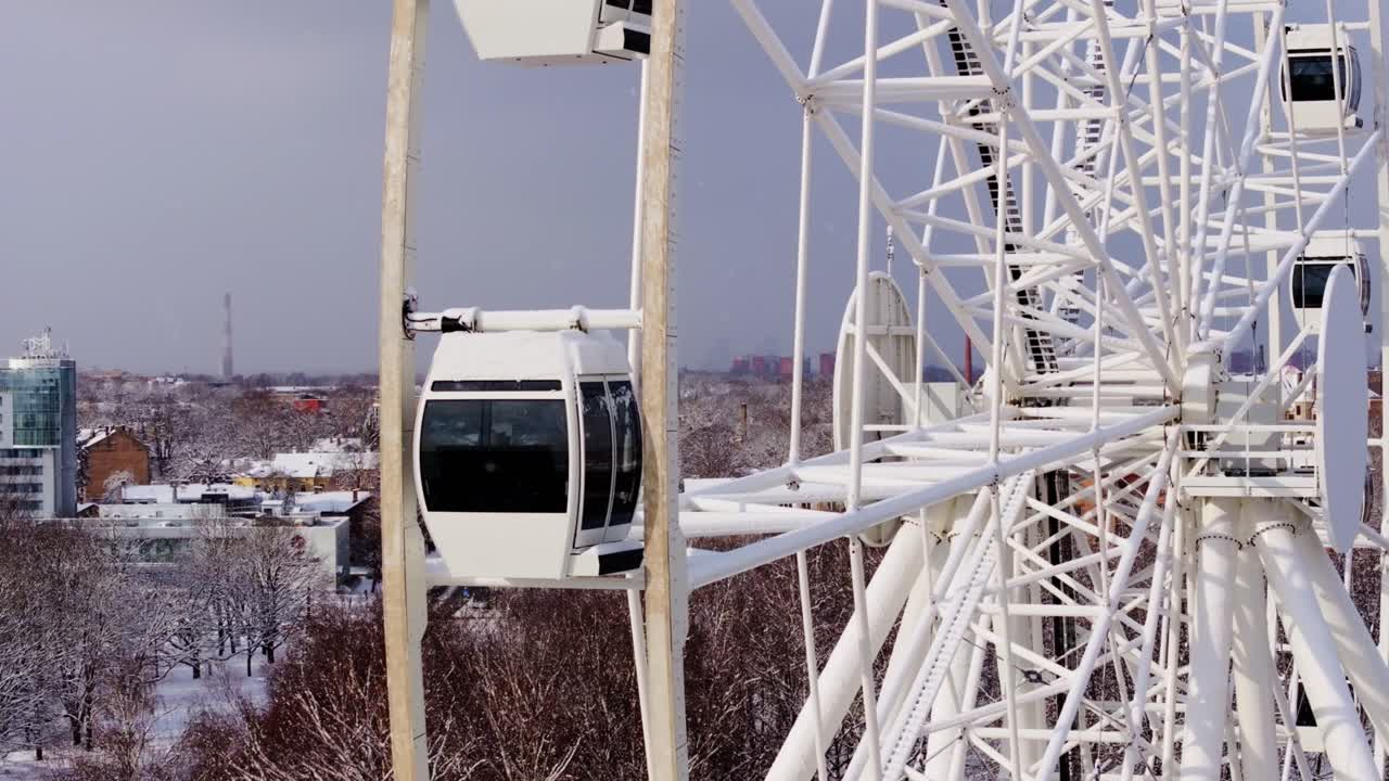 Telephoto shot of Ferris wheel, snowy Riga city skyline during winter snowfall