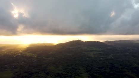 Golden-sunshine-glowing-on-horizon-at-beautiful-sunrise-on-Kauai-Hawaii-island-under-tropical-rain-clouds