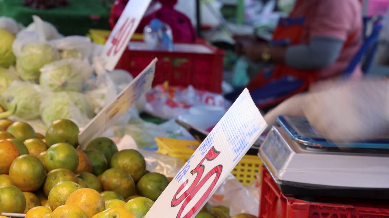 Person selects and purchases fresh oranges at colorful outdoor market, natural lighting, handheld camera