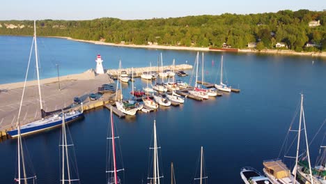 a marina in a cove in georgian bay with yachts and other kinds of boats, a lighthouse on the dock, quebec, canada