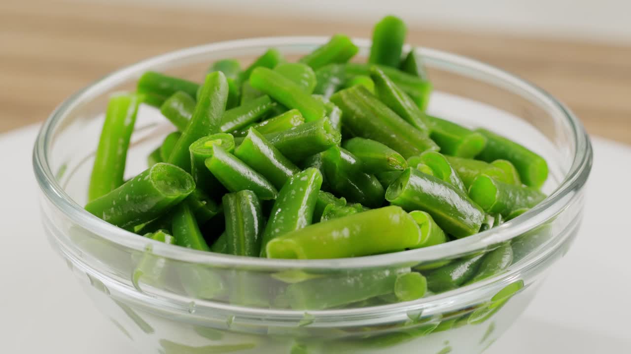 Fried wok green beans with onions and spices in a white plate on a gray background. Flat lay. Top view. High quality 4k footage
