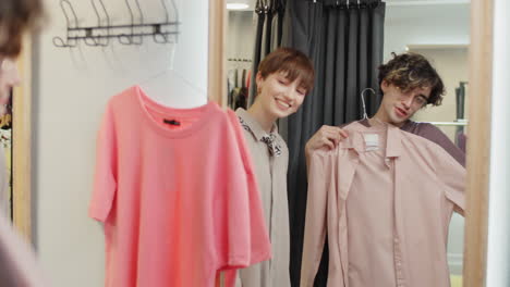 female assistant helping man with choosing clothes in dressing room