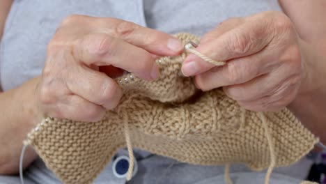 primer plano de tejer, una abuela teje calcetines de lana cálidos para sus nietos para el invierno. manos viejas cubiertas de arrugas se tejen con agujas de tejer. la costura es un pasatiempo de los jubilados