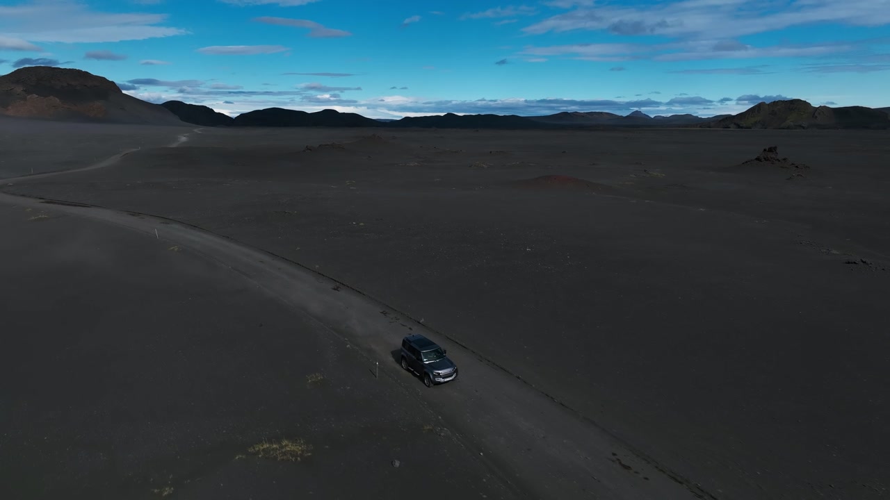 Fast car in black desert. SUV vehicle driving through volcanic sand.