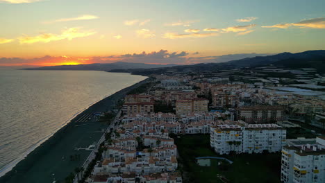 Aerial-drone-backward-moving-shot-of-beautiful-coast-of-Malaga-in-Spain-overlooking-the-sea-with-waves-crashing-during-evening-time