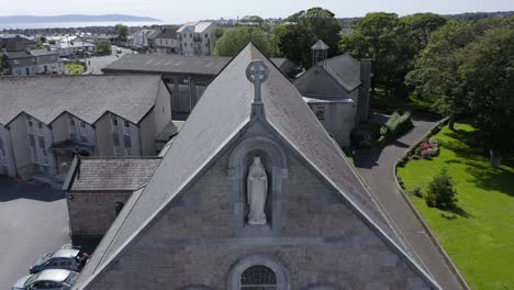 toma aérea de la iglesia de claddagh tirando hacia atrás e inclinándose hacia arriba desde el techo para revelar una vista impresionante del edificio que captura su grandeza y serenidad