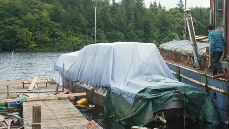 a man mooring a wooden boat with covers to a dock