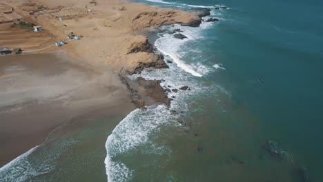 waves splashing on rocky beach in the town of lobitos in peru on a sunny summer day