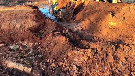 earth-moving equipment creating a trench for water flow, enabling smooth drainage and foundation connections in construction project