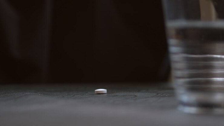 Hand removes pill from pack on table hesitates before taking, macro