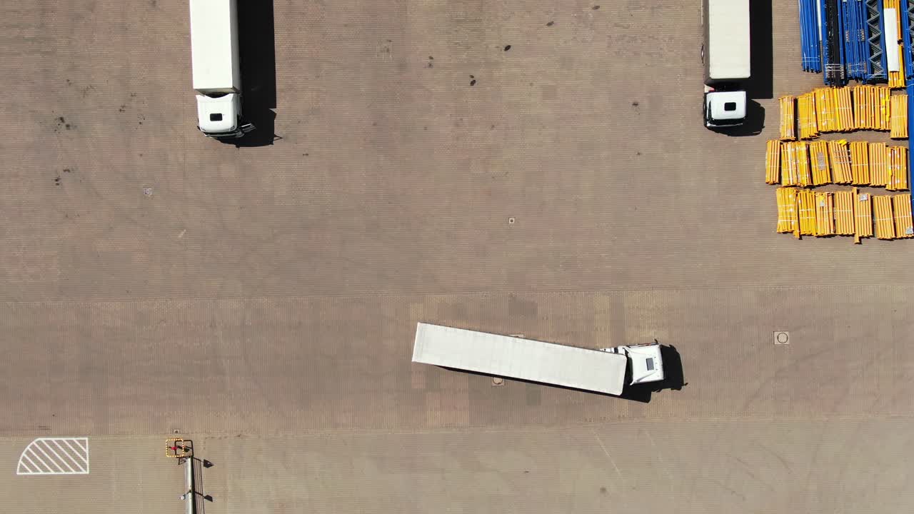 화물 트레일러가 있는 세미 트럭이 물류 공원의 창고 주차장을 따라 이동하고 있습니다.