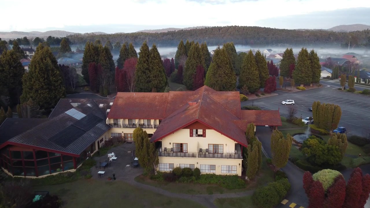 霧深い森を背景にしたヨーロッパ様式の建物の空撮。