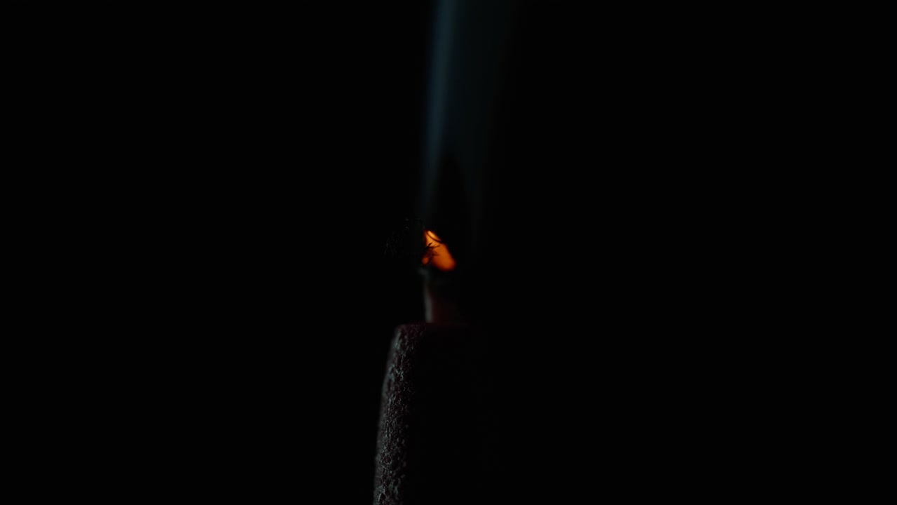 Closeup extinguished candle smoke. Wax taper blowing out on black background