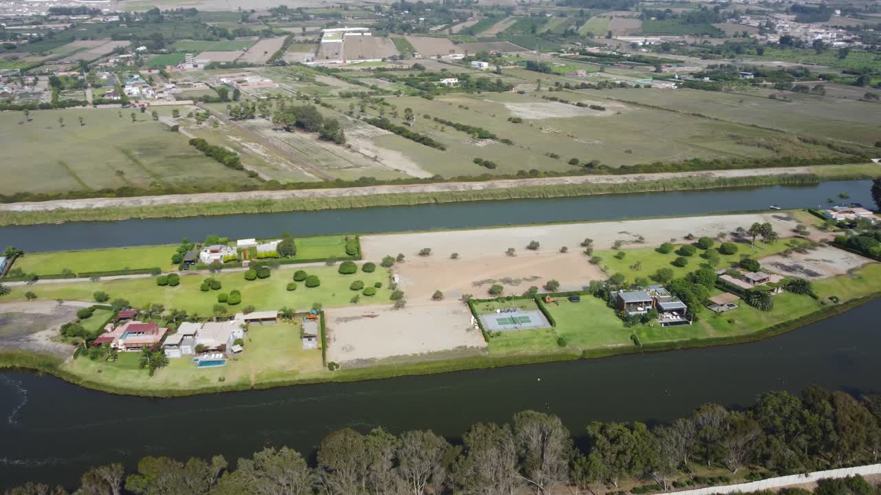 drone orbitando alrededor de un lago artificial hecho por el hombre con campos y casas en medio de la laguna