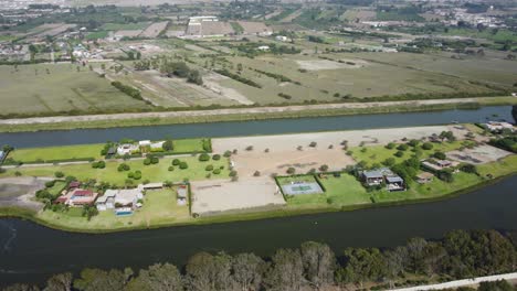 drone orbitando alrededor de un lago artificial hecho por el hombre con campos y casas en medio de la laguna