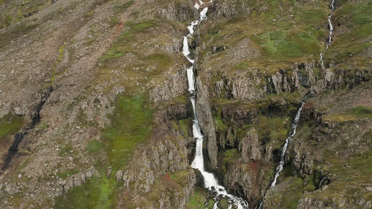 cascada de agua derretida en la ladera rocosa de la remota montaña de islandia, antena