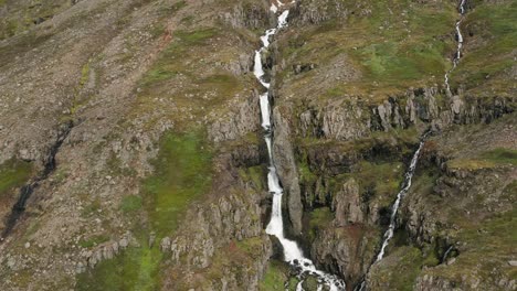 cascada de agua derretida en la ladera rocosa de la remota montaña de islandia, antena